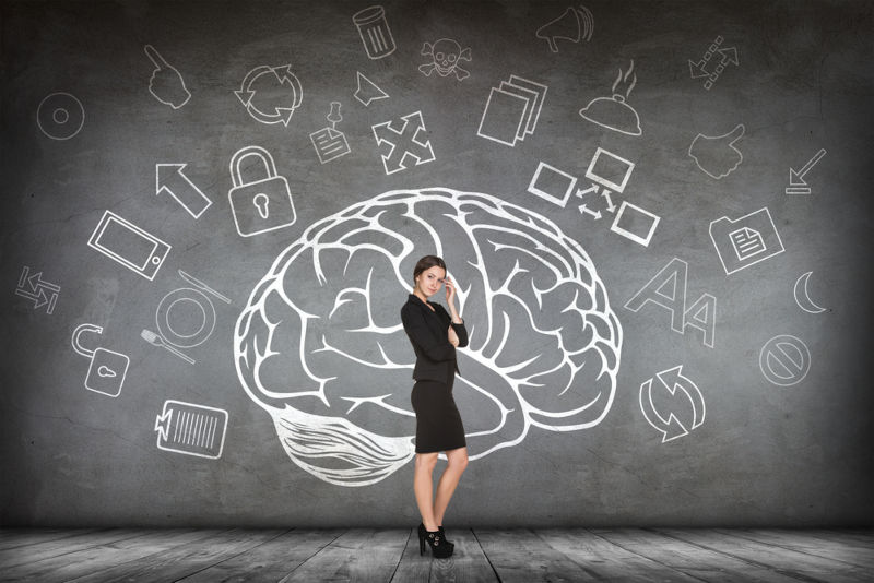 A future educational leader standing in front of a drawing of a brain representing the knowledge gained in an EdD program