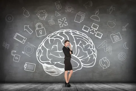 A future educational leader standing in front of a drawing of a brain representing the knowledge gained in an EdD program